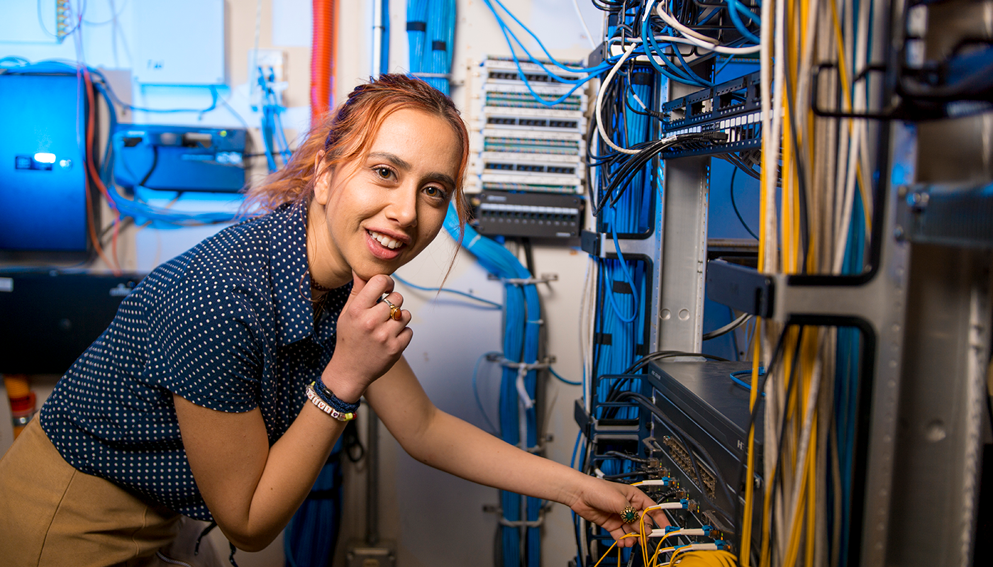 A Computer Information Systems student working on wires to servers.